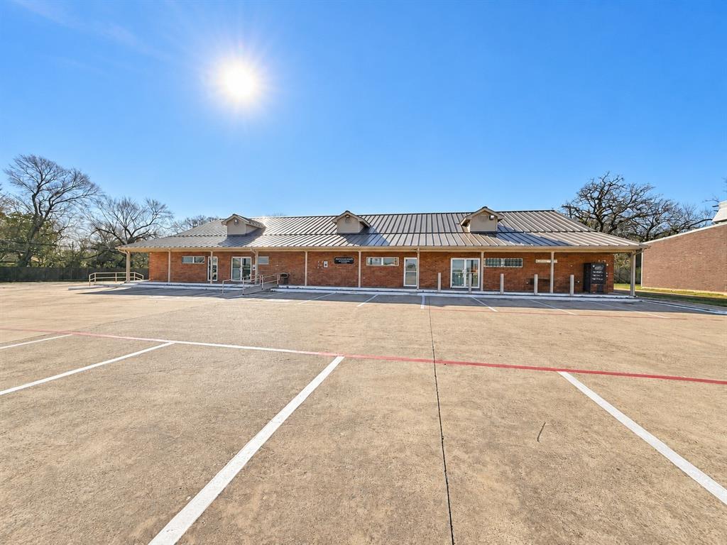 Single-story brick medical office building at 112 Hall Rd with a metal roof, covered walkway, and a large freshly striped parking lot